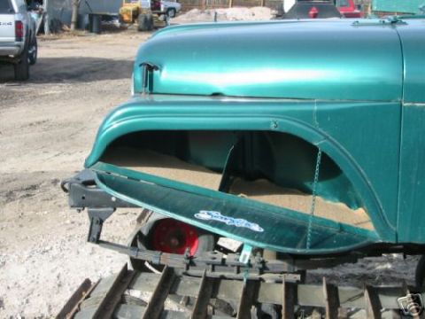 2000 Ford E350 - A vintage green jeep is shown with its side storage compartment open, revealing sand inside. It is equipped with tracks instead of wheels.