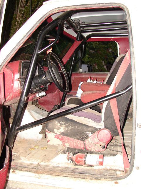 1996 Ford Bronco - The interior of this vehicle features a prominent roll cage, racing seats, and a fire extinguisher visible on the floor.