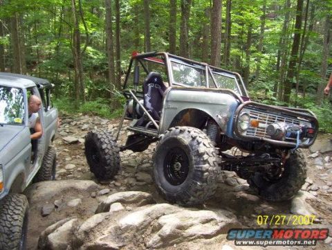 1992 Ford Mustang - Two off-road vehicles navigate a rocky trail in a wooded area.