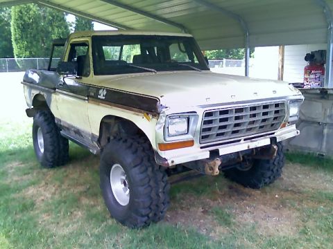 1979 Ford Bronco - This lifted Ford pickup truck, likely a 1978 model based on its grille, is parked under a carport.