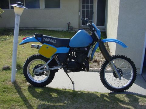 1994 Ford Bronco - A blue Yamaha dirt bike with yellow accents is parked on a paved surface next to a house.