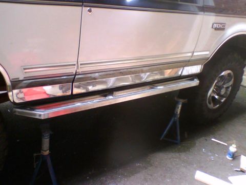 1993 Ford Bronco - A 1993 Ford Bronco is shown from the side, lifted on jack stands with chrome running boards visible.