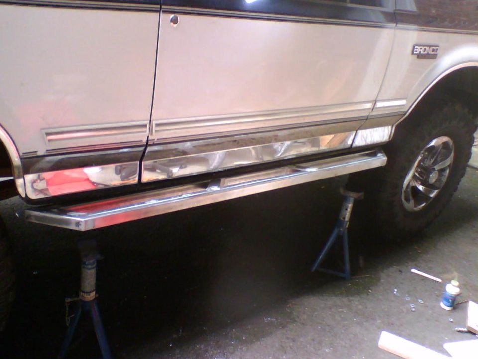 1993 Ford Bronco side view, silver body with chrome trim and running boards, on jack stands