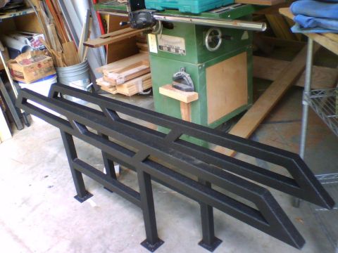1993 Ford Bronco - These black metal rock sliders feature an angular, geometric design and are shown in a workshop setting.