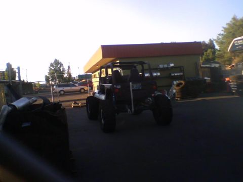 1993 Ford Bronco - A heavily modified off-road vehicle is seen from the rear, parked outdoors near a commercial building.