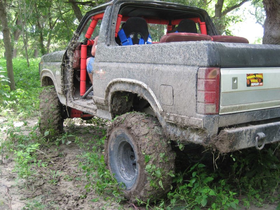 Muddy SUV with roll cage, off-roading in woods