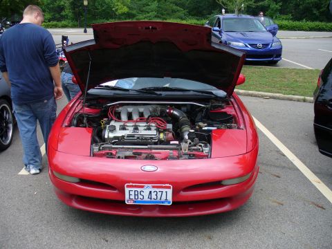 1991 Ford Probe - Front view of a red 1991 Ford Probe, engine exposed, with a blue Mazda 6 in the background.