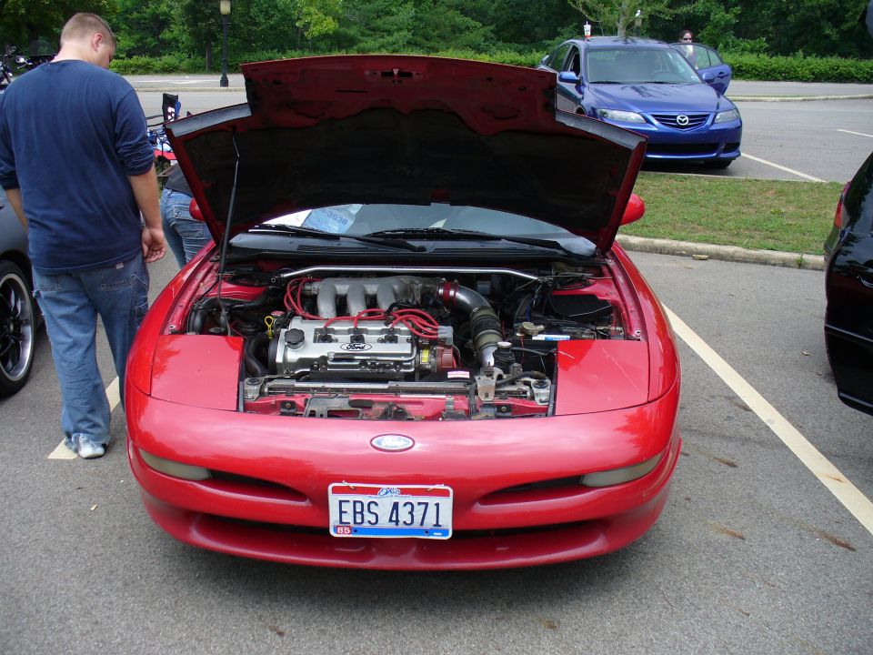 Red 1991 Ford Probe with hood open, showing engine. Blue Mazda 6 parked behind