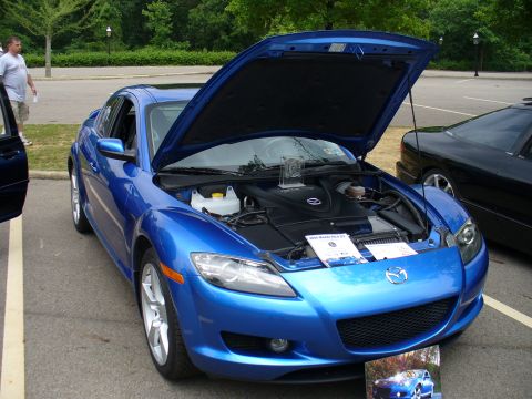 1991 Ford Probe - A blue Mazda RX-8 is displayed with its hood open, revealing the engine compartment and a sign indicating it is a 2004 model.