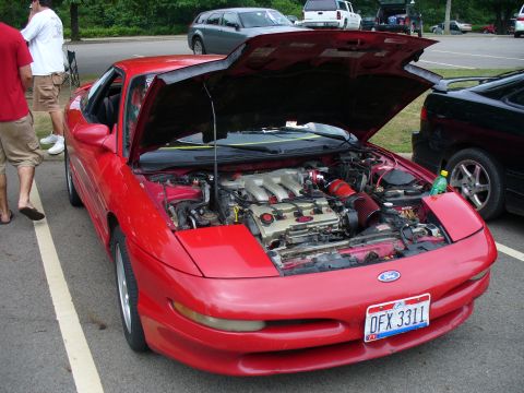 1991 Ford Probe - The engine bay of a red 1991 Ford Probe is displayed with the hood fully open.