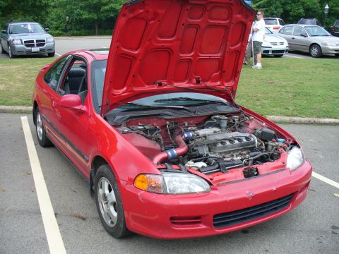 1991 Ford Probe - A red coupe is parked with its hood open, revealing the engine bay. Other vehicles are visible in the background.