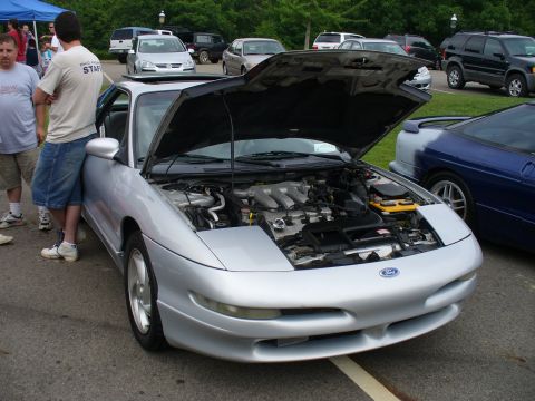 1991 Ford Probe - A silver 1991 Ford Probe is displayed with its hood open, revealing the engine compartment. Other vehicles are visible in the background.