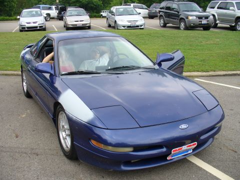 1991 Ford Probe - A blue Ford Probe is parked in a lot with other vehicles visible in the background.