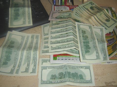 2006 Ford F1 - US currency is spread across a desk surface, partially obscuring a calendar and keyboard.