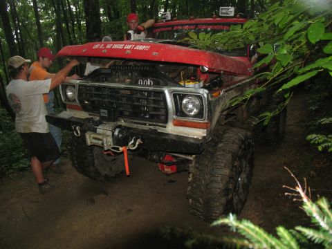 1995 Ford C-350 (Centurion Conversions) - Off-road truck with hood open, being worked on by three people in a wooded area.
