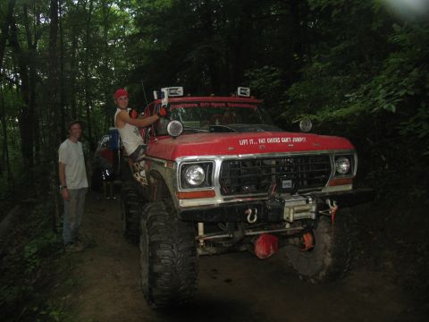 1995 Ford C-350 (Centurion Conversions) - This heavily modified red Ford truck features oversized off-road tires and a humorous decal on its hood.
