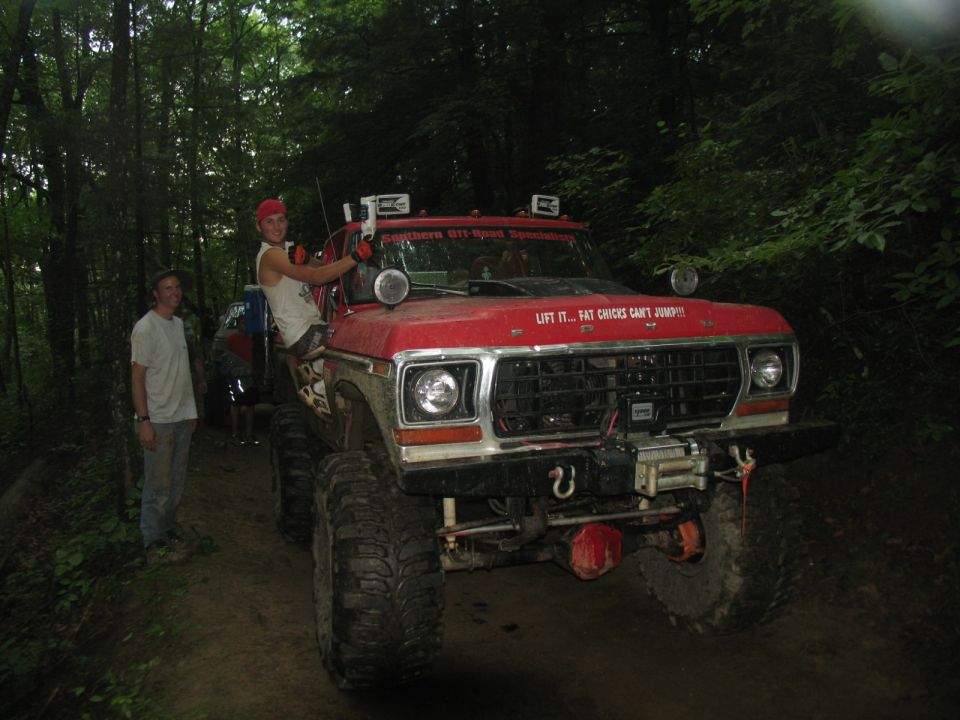 Red lifted Ford truck with off-road tires and "LIFT IT... FAT CHICKS CAN'T JUMP!" decal