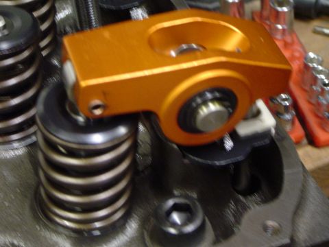 1978 Ford Bronco - Close-up of an engine part: an orange roller rocker arm positioned on a valve spring.
