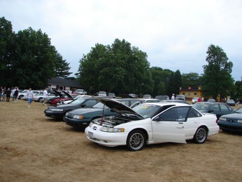 1993 Ford Taurus - Cars gathered for a car show, with several models on display and their hoods open.