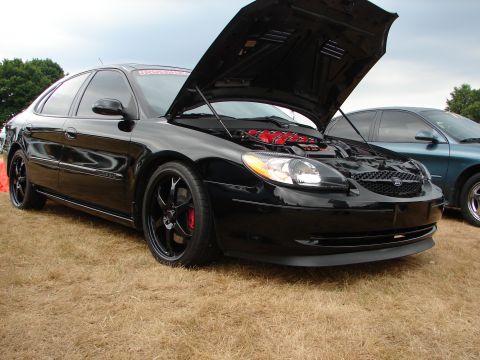 1993 Ford Taurus - Black sedan with hood open, revealing red engine components. Another car is visible in the background.