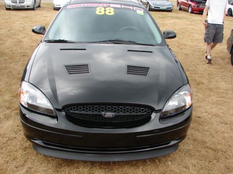1993 Ford Taurus - A black Ford Taurus is parked on a grassy field with other vehicles visible in the background.