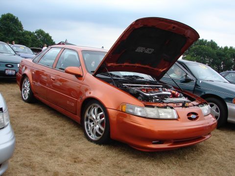 1993 Ford Taurus - This 1993 Ford Taurus SHO features an orange exterior and an open hood revealing its engine and SHO badging.