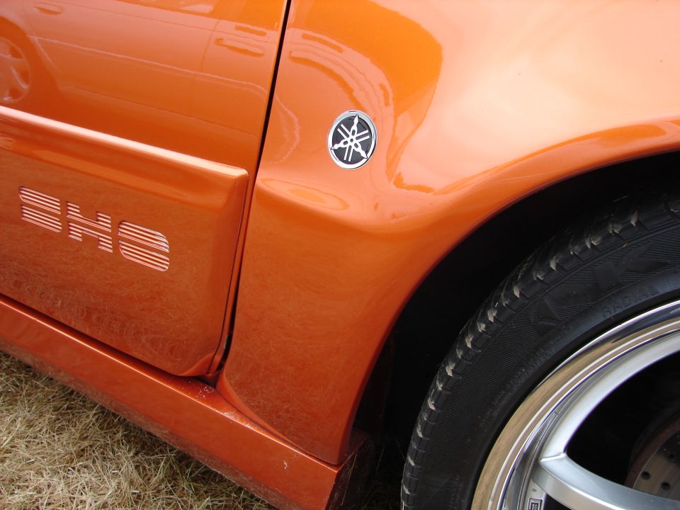 Orange car door with "SHO" text and Yamaha emblem, close-up side view
