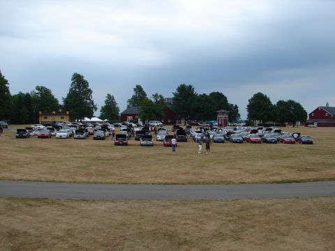 1993 Ford Taurus - A car show event is taking place on a large, dry grass field with numerous vehicles on display.