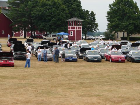 1993 Ford Taurus - A gathering of Ford Taurus vehicles, likely at a car show, with attendees observing the cars.