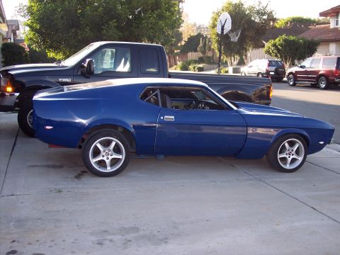 1971 Ford Mustang - A blue 1971 Ford Mustang coupe is parked next to a black pickup truck in a suburban driveway.