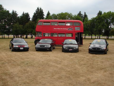 1993 Ford Taurus - A collection of Ford Taurus sedans are displayed in front of a vintage London double-decker bus.