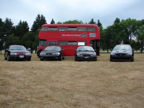 1993 Ford Taurus - Four Ford Taurus sedans are lined up in front of a red double-decker bus.