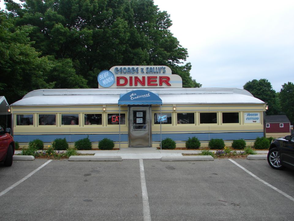 George & Sally's Diner with Blue Moon sign, yellow and blue exterior, parked cars
