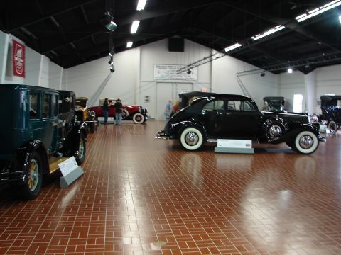 1993 Ford Taurus - Several vintage cars are on display inside a building with a high ceiling and brick floor.