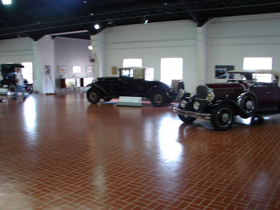 Several vintage automobiles displayed indoors on a tiled floor