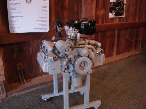 1993 Ford Taurus - Engine displayed on a stand, with a document and a framed photo on the wall behind it.