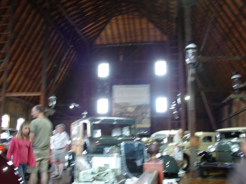 1993 Ford Taurus - A collection of antique vehicles are displayed within a rustic barn setting.