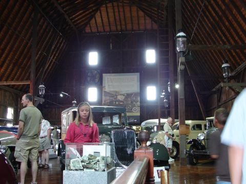 1993 Ford Taurus - A collection of antique automobiles are displayed inside a rustic barn, with visitors observing the exhibits.