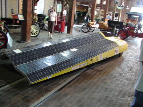 1993 Ford Taurus - A yellow solar-powered car is displayed indoors, covered in solar panels.