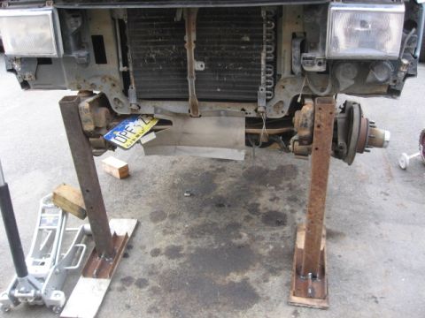 1990 Ford F-250 - The front clip of a truck is elevated on jack stands, revealing the radiator and suspension components.
