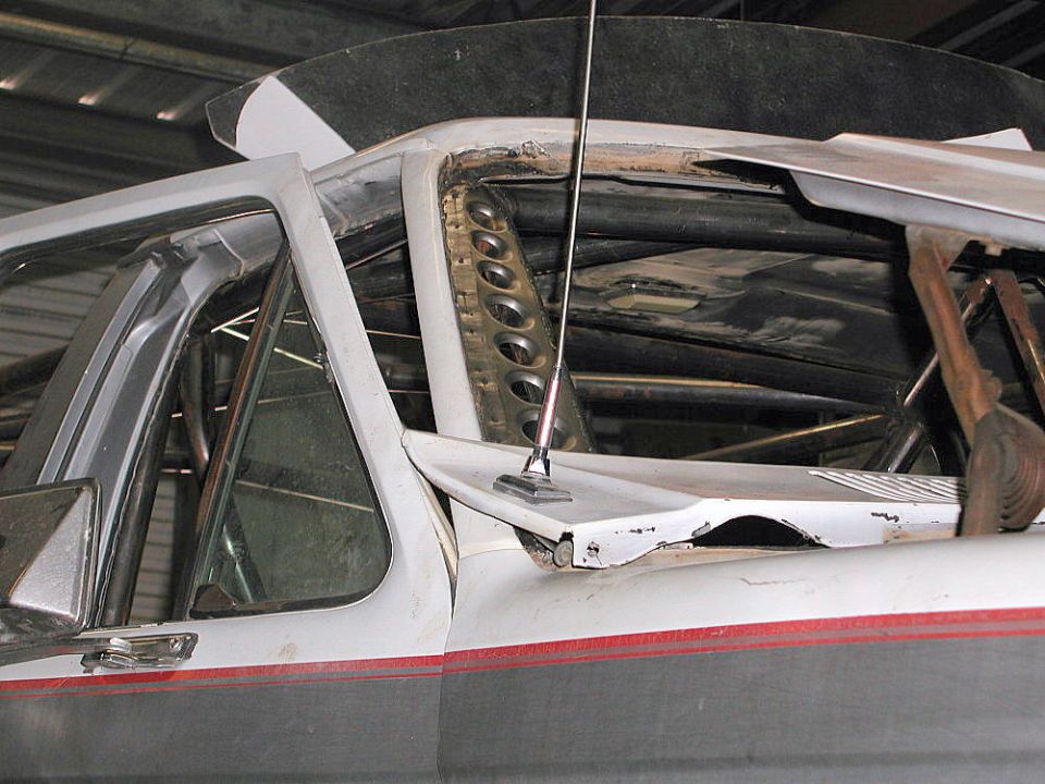 Modified vehicle interior showing roll cage, antenna mount, and part of the dashboard