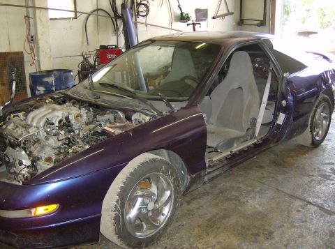 1996 Ford Probe - This purple car is missing its doors and has its engine exposed, indicating it is likely a project or parts vehicle.