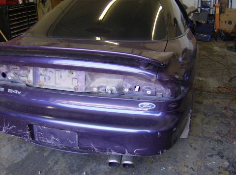 1996 Ford Probe - The rear of a purple Ford Probe is shown in a garage setting, with visible damage and missing body panels.