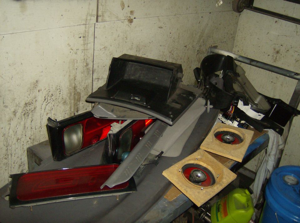 Car parts including red tail lights, a black glove box, and two speakers on wooden mounts