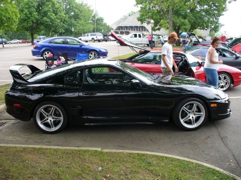 1991 Ford Probe - A black sports car with a distinctive rear spoiler is parked at an outdoor event.