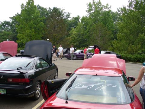 1991 Ford Probe - People gather around cars with their hoods open at an outdoor event.