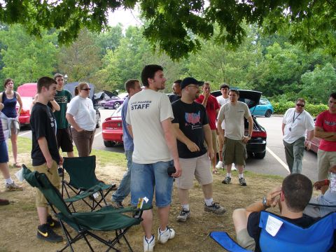 1991 Ford Probe - A gathering of people outdoors with several vehicles parked in the background.