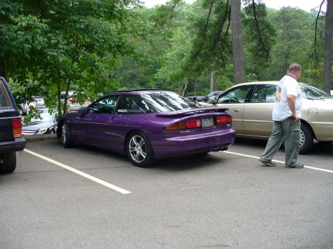 1991 Ford Probe - A purple 1991 Ford Probe is parked in a lot next to another car, with a man walking away from the camera.
