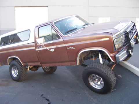 1991 Ford Bronco - This lifted pickup truck has a custom trim package and a white camper shell.