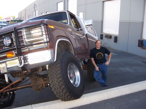 1991 Ford Bronco - Man poses with a heavily modified lifted Ford pickup truck, likely from the early 1980s.